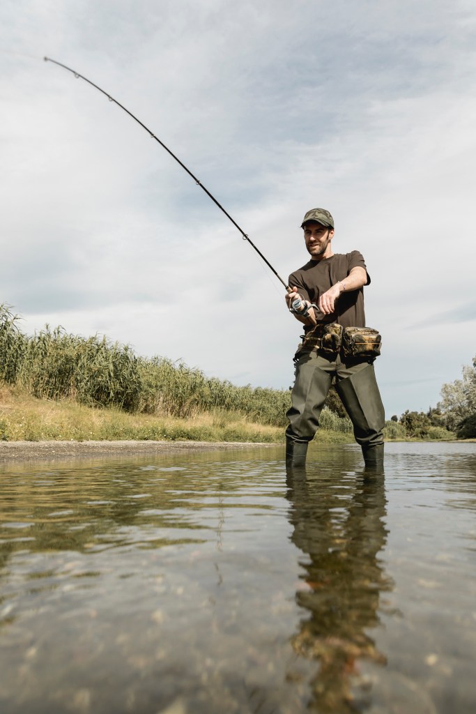 Man fly fishing in river, representing regenerative agriculture lifestyle and nature connection.